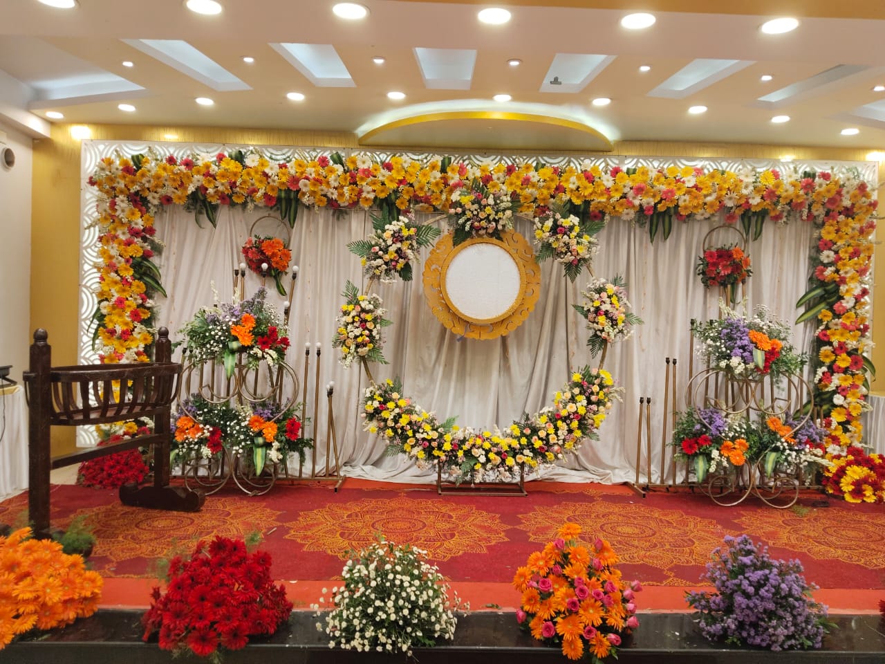 Grand marigold wedding stage with floral garlands and warm golden lighting by Kanishk Events